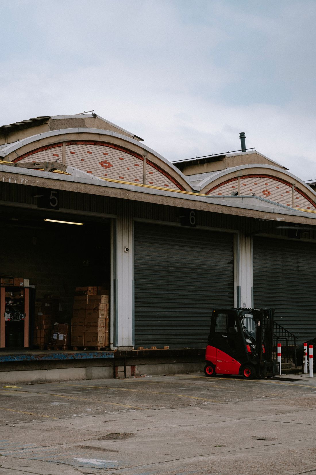 Forklift working beside commercial roll-up doors in a warehouse